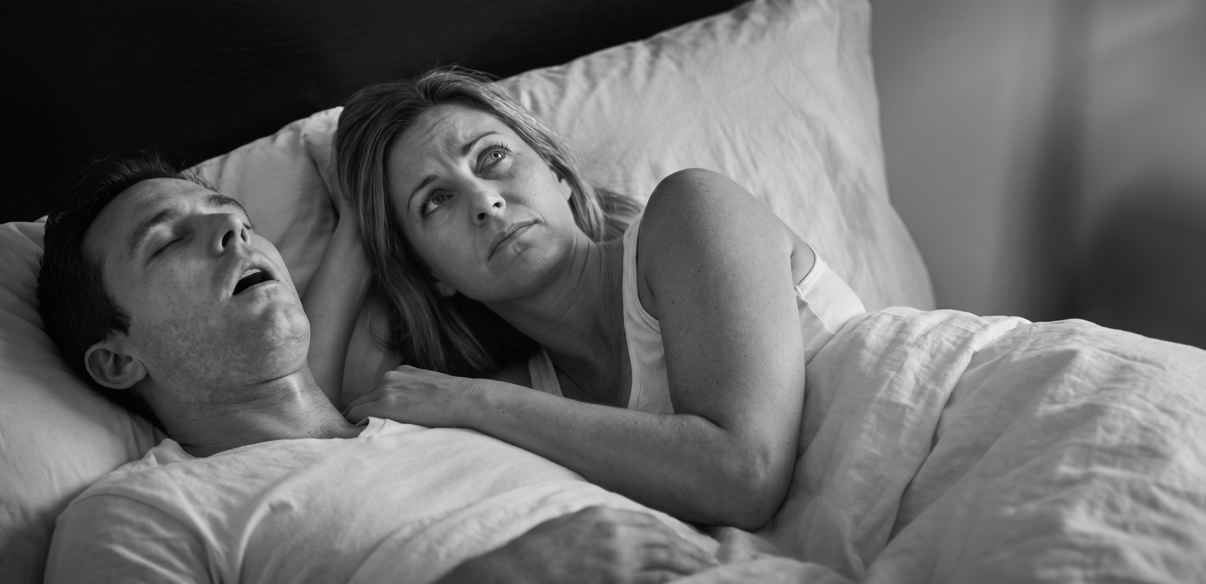 person snoring in bed causing partner sleep disruption
